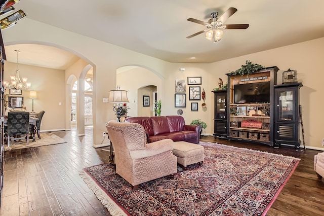 living area with baseboards, arched walkways, dark wood-style flooring, and ceiling fan with notable chandelier