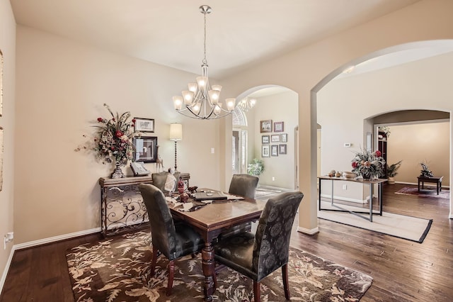 dining space with arched walkways, hardwood / wood-style floors, an inviting chandelier, and baseboards