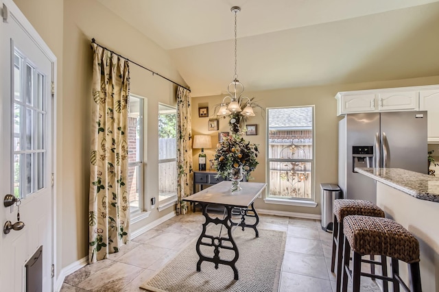 dining area featuring plenty of natural light, vaulted ceiling, and baseboards