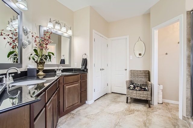 bathroom featuring double vanity, a sink, and baseboards