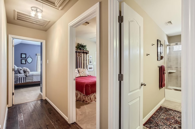 hall with dark wood finished floors, visible vents, and baseboards