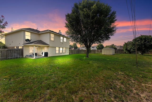 yard at dusk featuring a patio and a storage shed