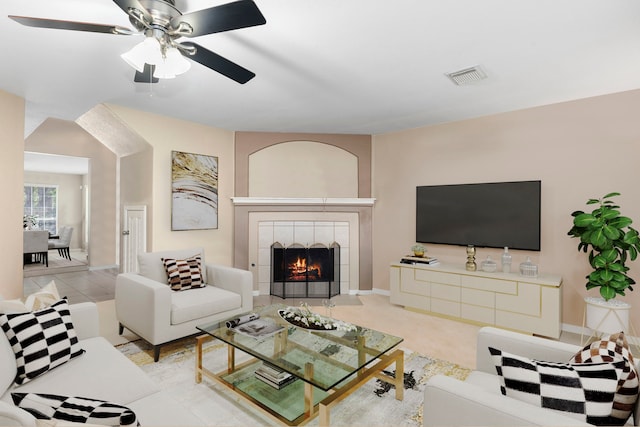 living room with ceiling fan and a tiled fireplace