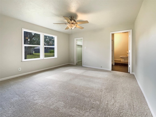 unfurnished bedroom with ceiling fan, ensuite bathroom, carpet floors, a walk in closet, and a closet