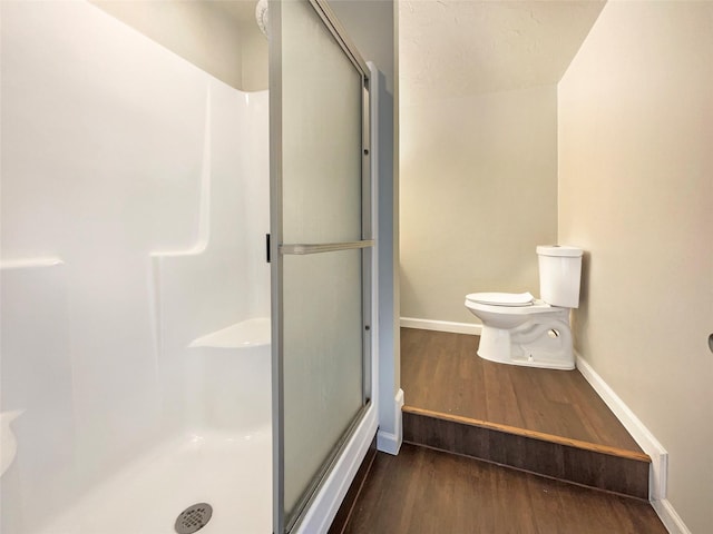 bathroom featuring hardwood / wood-style flooring, toilet, and an enclosed shower