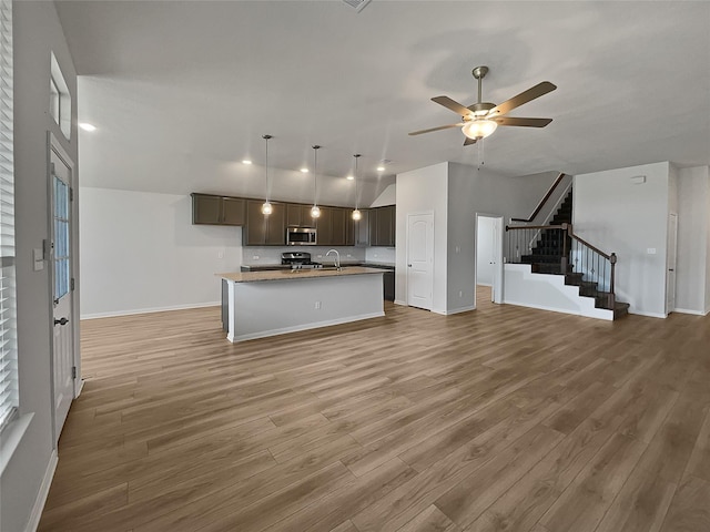 kitchen featuring ceiling fan, sink, stainless steel appliances, a center island with sink, and hardwood / wood-style flooring