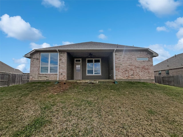 rear view of property with ceiling fan and a yard