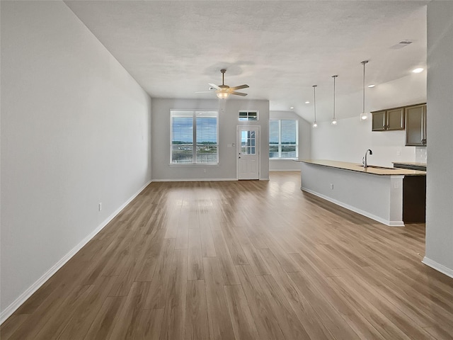 unfurnished living room featuring vaulted ceiling, ceiling fan, dark hardwood / wood-style flooring, and a textured ceiling