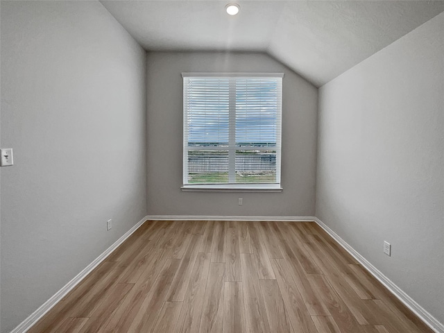 unfurnished room featuring plenty of natural light, light wood-type flooring, and lofted ceiling