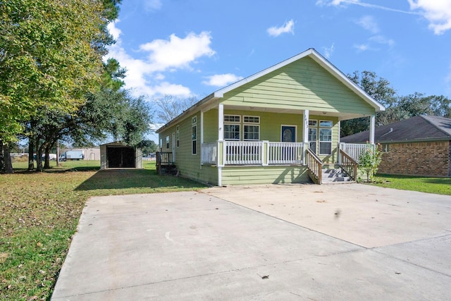 bungalow-style home featuring covered porch, a front yard, and a storage unit