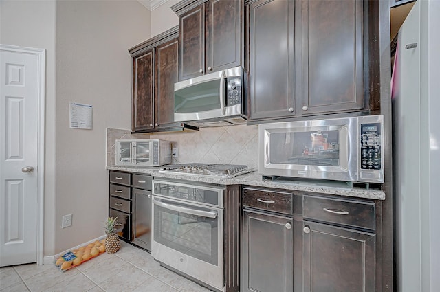 kitchen with light stone countertops, stainless steel appliances, light tile patterned floors, backsplash, and dark brown cabinets