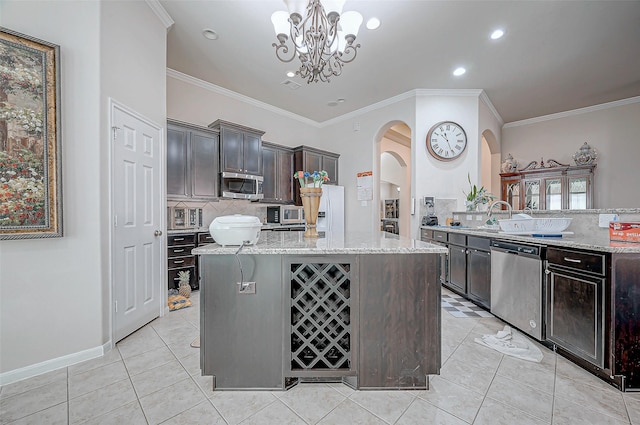 kitchen with stainless steel appliances, decorative light fixtures, light stone countertops, and dark brown cabinetry