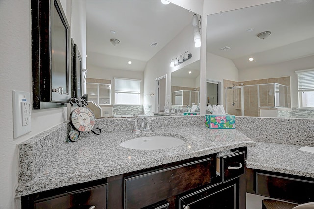 bathroom featuring a shower with door, vaulted ceiling, and vanity