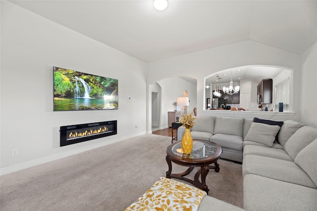 carpeted living room with a chandelier and lofted ceiling