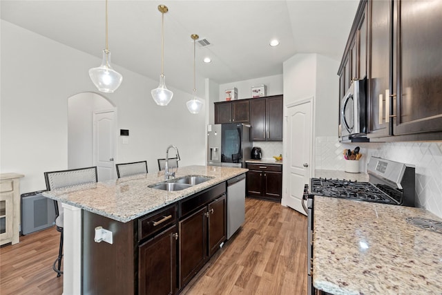 kitchen with decorative backsplash, a kitchen island with sink, sink, and stainless steel appliances