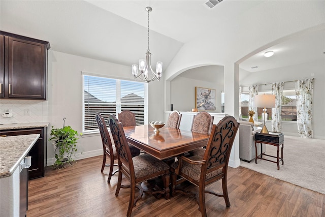 dining room featuring a notable chandelier, dark hardwood / wood-style flooring, and vaulted ceiling