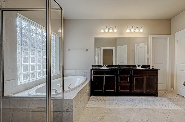 bathroom with tiled tub, tile patterned flooring, vanity, and plenty of natural light