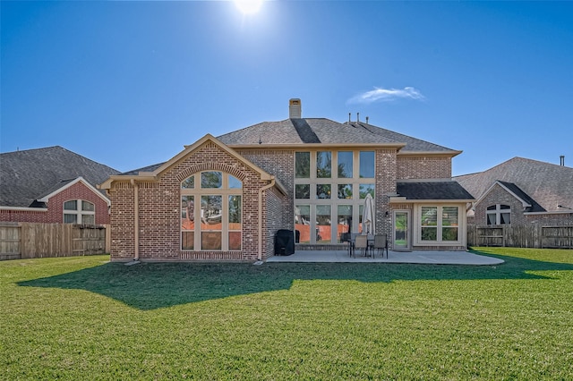 rear view of house featuring a lawn and a patio