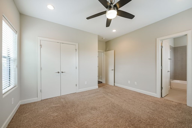 unfurnished bedroom with ensuite bath, ceiling fan, a closet, and light colored carpet