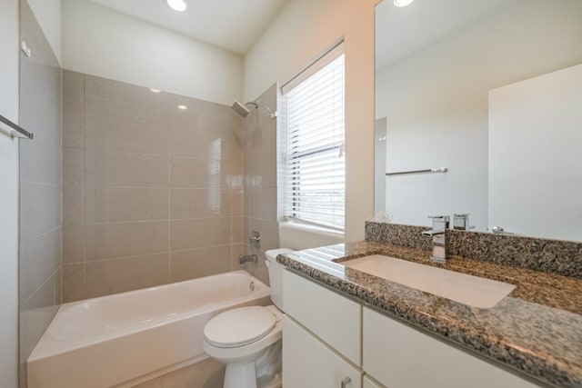 full bathroom featuring tiled shower / bath combo, toilet, and vanity