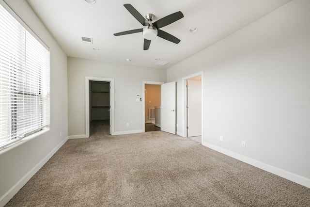 unfurnished bedroom featuring carpet flooring, ceiling fan, a spacious closet, and a closet