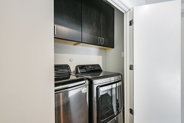 clothes washing area with cabinets and washing machine and clothes dryer