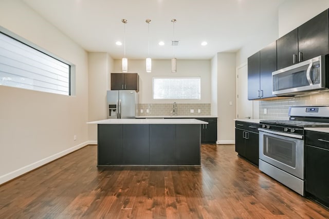 kitchen featuring dark hardwood / wood-style flooring, a kitchen island, pendant lighting, and appliances with stainless steel finishes