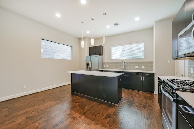 kitchen featuring stainless steel appliances, tasteful backsplash, dark hardwood / wood-style flooring, pendant lighting, and a kitchen island