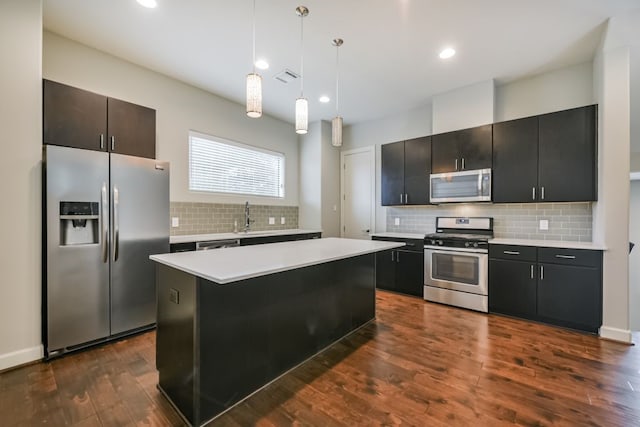 kitchen featuring a kitchen island, stainless steel appliances, hanging light fixtures, and dark wood-type flooring