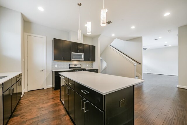 kitchen featuring hanging light fixtures, stainless steel appliances, dark hardwood / wood-style flooring, backsplash, and a kitchen island