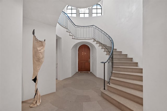 stairway featuring a towering ceiling