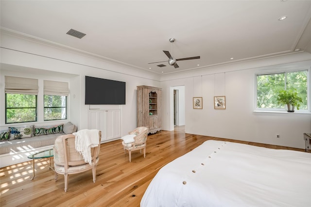 bedroom featuring ceiling fan, light wood-type flooring, ornamental molding, and multiple windows