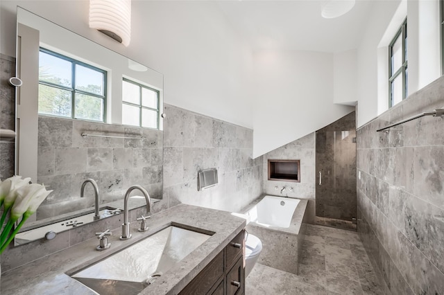 bathroom with tiled bath, vanity, tile walls, and toilet