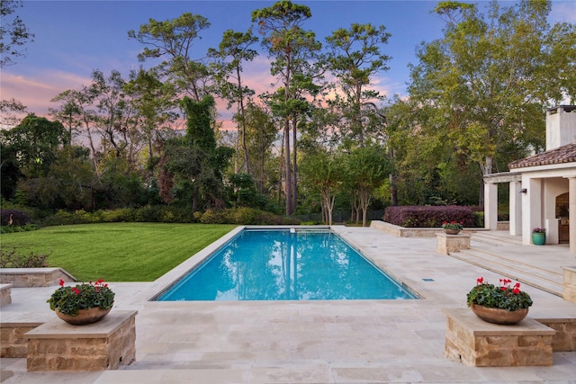 pool at dusk featuring a yard and a patio area