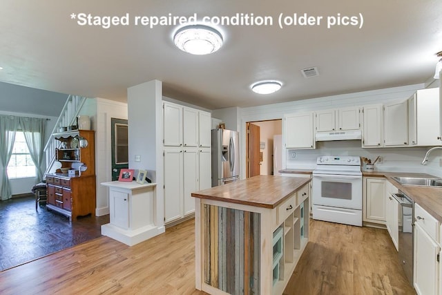 kitchen with stainless steel appliances, visible vents, a sink, wood counters, and under cabinet range hood