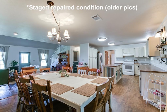 dining space featuring sink, hardwood / wood-style floors, and a chandelier