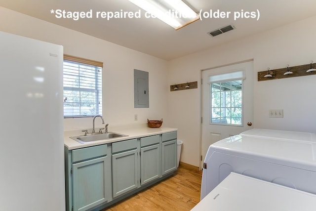 laundry room featuring electric panel, visible vents, washer and clothes dryer, light wood-style flooring, and a sink