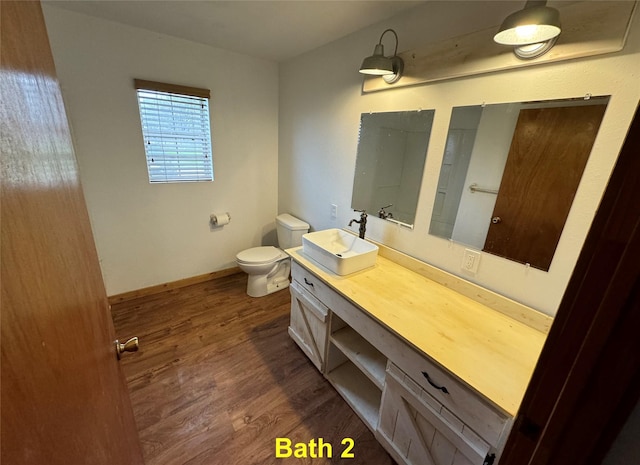 bathroom with baseboards, vanity, toilet, and wood finished floors