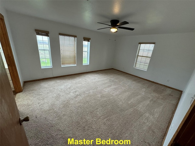 carpeted spare room with plenty of natural light, baseboards, and ceiling fan