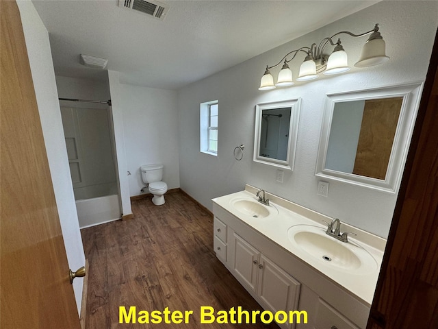 full bathroom with hardwood / wood-style floors, toilet, shower / tub combination, and vanity