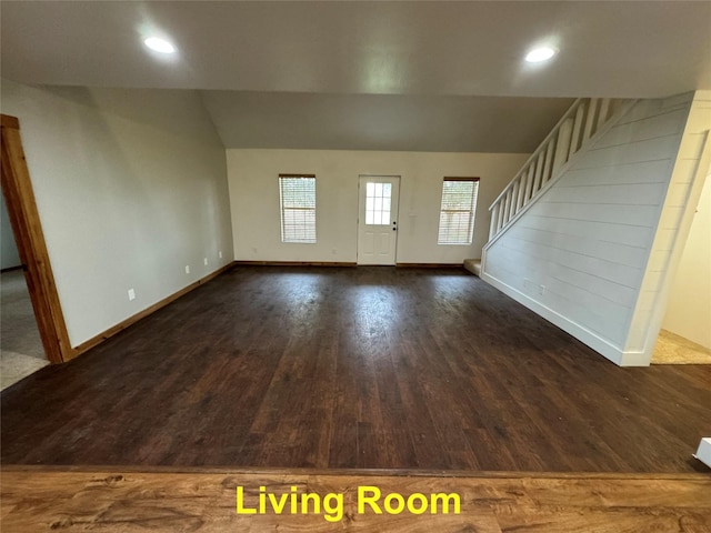 unfurnished living room with lofted ceiling, recessed lighting, wood finished floors, baseboards, and stairs