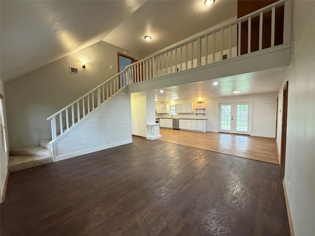 unfurnished living room with visible vents, dark wood-style floors, stairs, french doors, and high vaulted ceiling