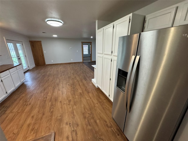 kitchen featuring dark wood-type flooring, a healthy amount of sunlight, white cabinets, and stainless steel refrigerator with ice dispenser