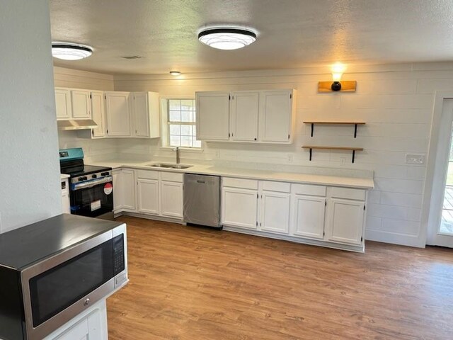 kitchen featuring stainless steel appliances, a sink, white cabinetry, light wood-type flooring, and open shelves