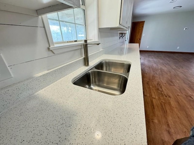 details with light countertops, a sink, baseboards, and white cabinetry