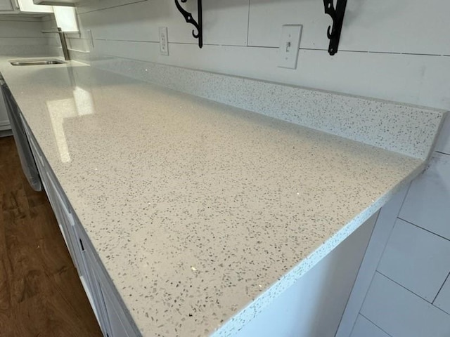 details with light stone countertops, dark wood finished floors, and a sink