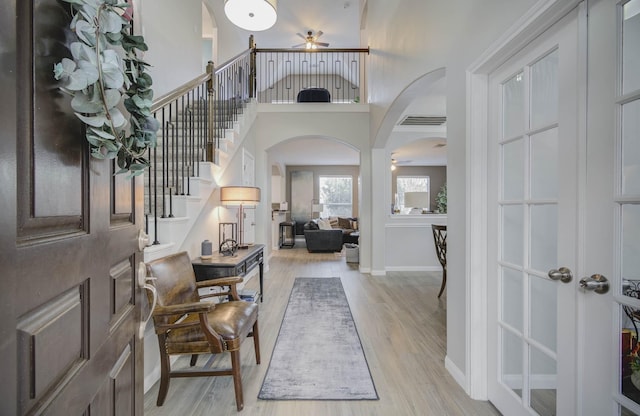 foyer entrance featuring a towering ceiling, light hardwood / wood-style floors, and ceiling fan