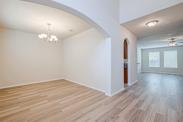 unfurnished room featuring ceiling fan with notable chandelier and light wood-type flooring