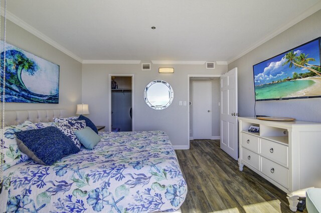 bedroom featuring a walk in closet, crown molding, a closet, and dark hardwood / wood-style floors