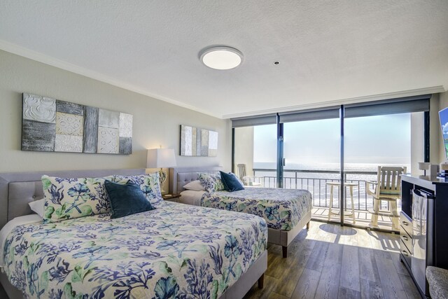 bedroom featuring access to exterior, dark wood-type flooring, expansive windows, a textured ceiling, and ornamental molding